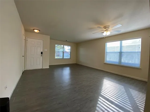 a view of an empty room with a window and wooden floor