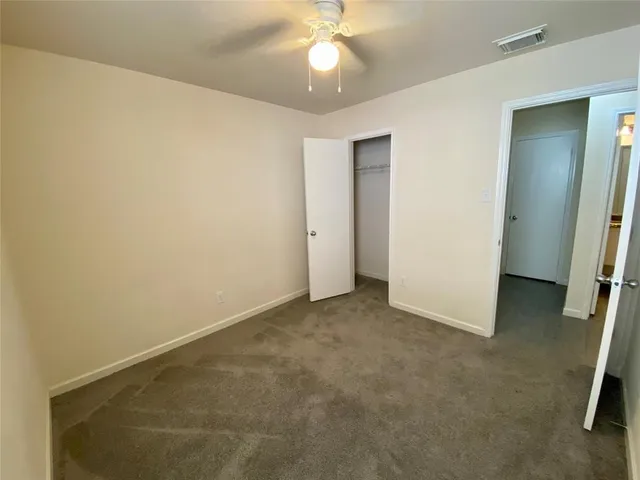 an empty room with closet and a chandelier fan