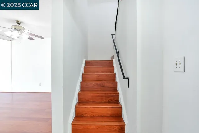 a view of an empty room with wooden floor and a bathroom