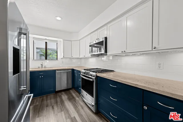 a kitchen with stainless steel appliances granite countertop a stove a sink and a refrigerator