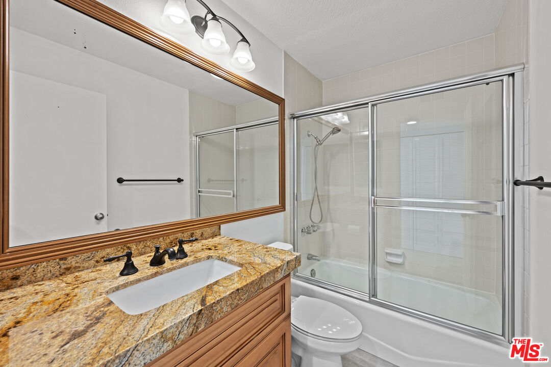 1312 South Saltair Avenue, Unit 215 Los Angeles, CA 90025 - Photo 20 of 31 a bathroom with a granite countertop sink a toilet and shower
