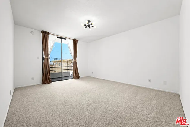 an empty room with chandelier fan and windows