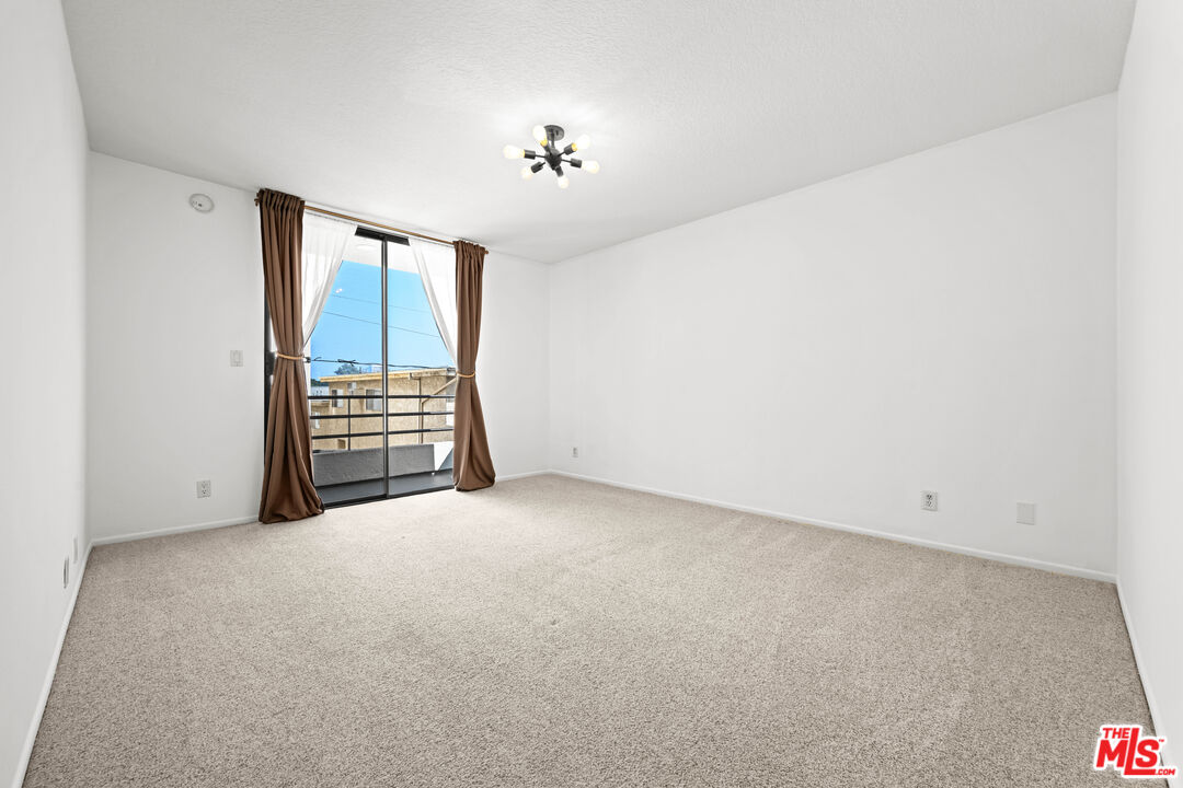 1312 South Saltair Avenue, Unit 215 Los Angeles, CA 90025 - Photo 23 of 31 an empty room with chandelier fan and windows