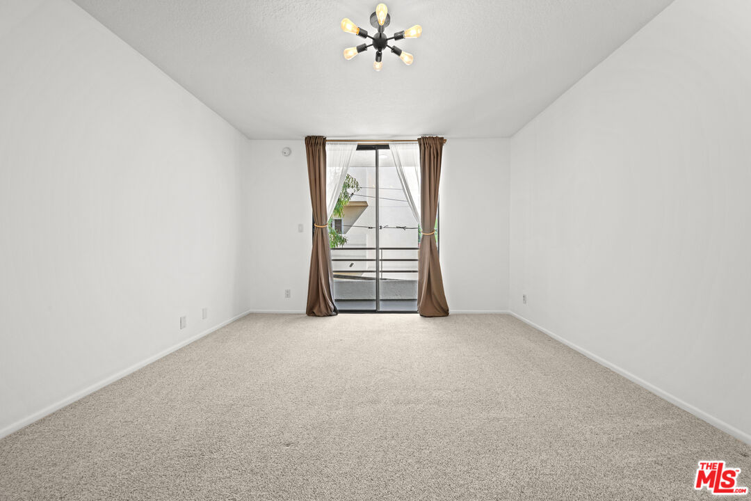 1312 South Saltair Avenue, Unit 215 Los Angeles, CA 90025 - Photo 24 of 31 an empty room with windows and chandelier fan