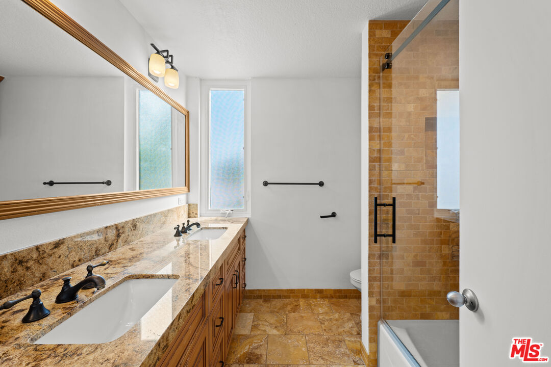 1312 South Saltair Avenue, Unit 215 Los Angeles, CA 90025 - Photo 26 of 31 a bathroom with a granite countertop tub sink and mirror