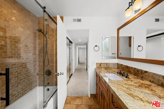 a bathroom with a granite countertop double vanity sink and mirror
