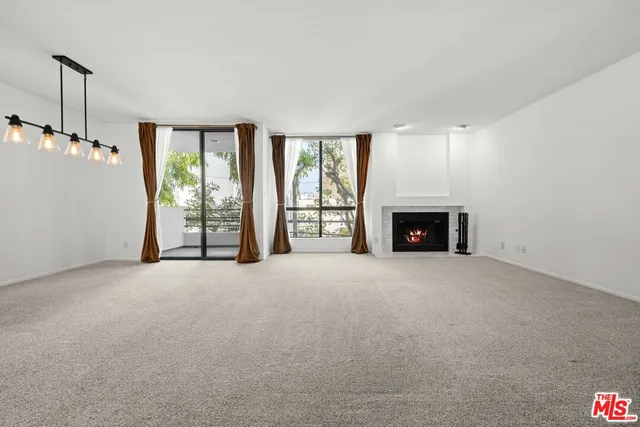 a view of an empty room with fireplace and a window