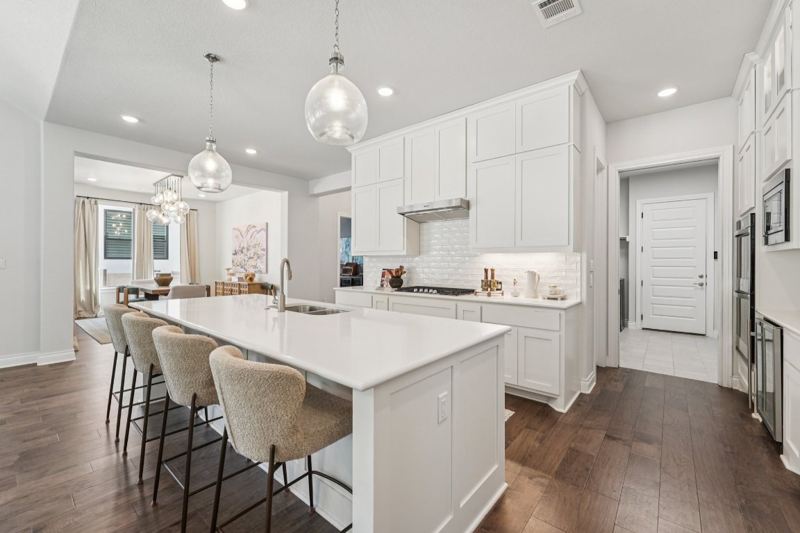 120 Hollytree Court Georgetown, TX 78628 - Photo 11 of 40 a kitchen with stainless steel appliances a table chairs in it and wooden floors