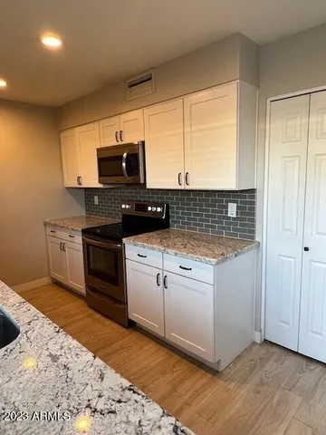 a kitchen with stainless steel appliances kitchen island granite countertop a sink cabinets and wooden floor