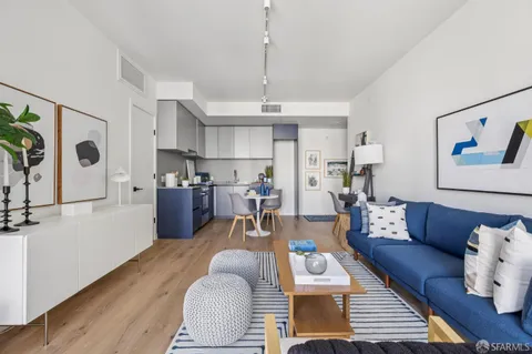 a living room with furniture kitchen view and a wooden floor