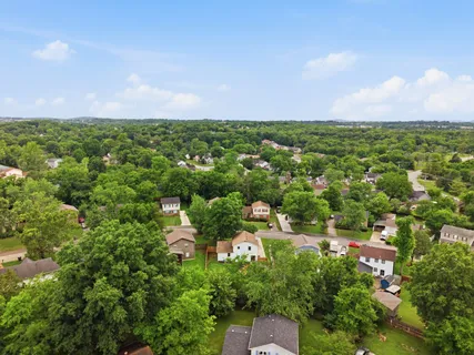 an aerial view of residential houses with outdoor space and trees