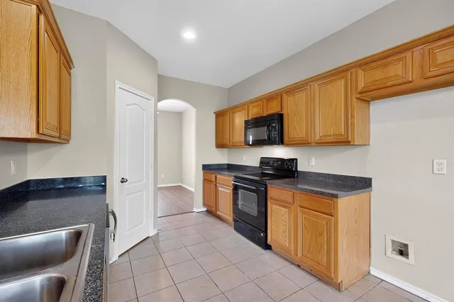 a kitchen with stainless steel appliances granite countertop a stove top oven a sink dishwasher and wooden cabinets with a granite countertops