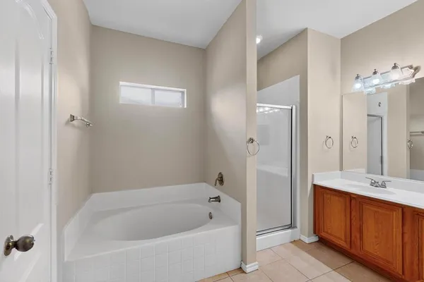 a bathroom with a tub a sink and a large mirror