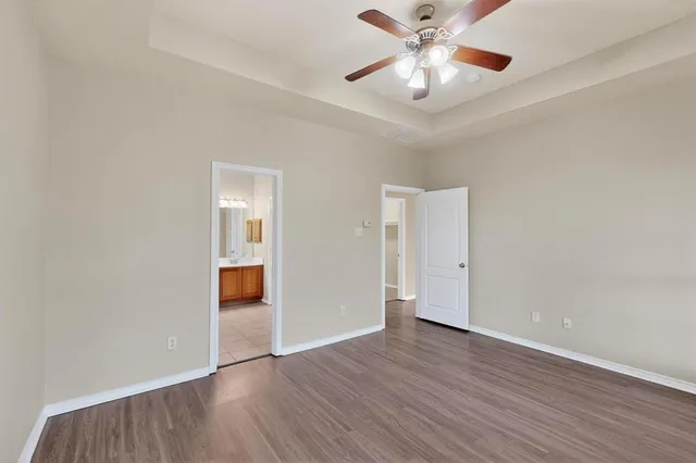 an empty room with wooden floor chandelier fan and windows