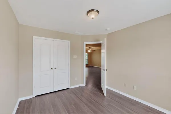 a view of an empty room with wooden floor and closet