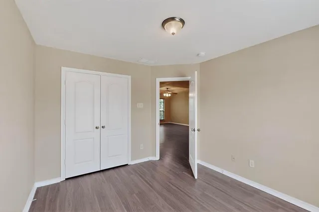 a view of an empty room with wooden floor and closet