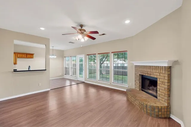 a view of an empty room with wooden floor and a fireplace