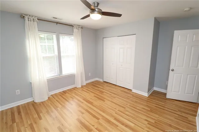 a view of empty room with wooden floor and fan
