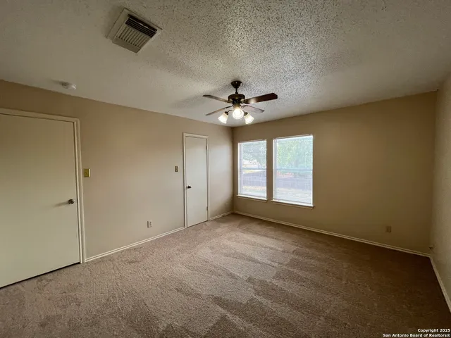 an empty room with windows and fan