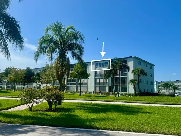 a view of a park that has a sign board with palm trees