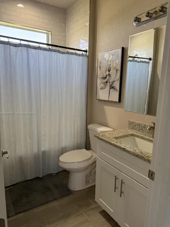 a bathroom with a granite countertop sink toilet and mirror