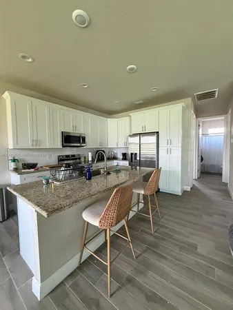 a kitchen with stainless steel appliances granite countertop a stove top oven a sink dishwasher a dining table and chairs with wooden floor