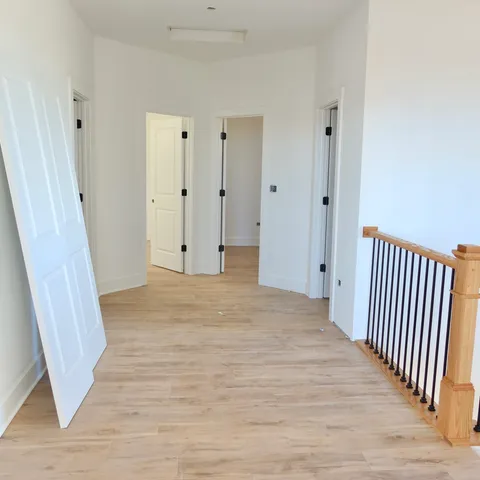 a view of a hallway with wooden floor and staircase