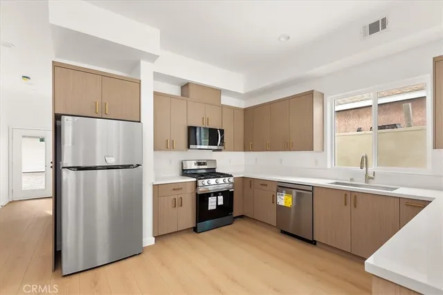 a view of a kitchen with wooden floor and electronic appliances