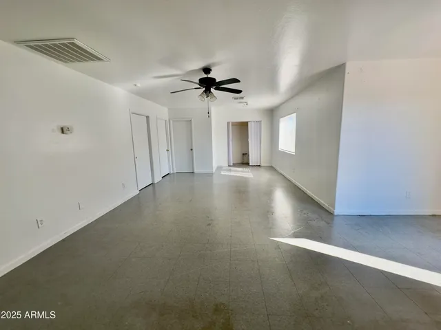 an empty room with windows and fan