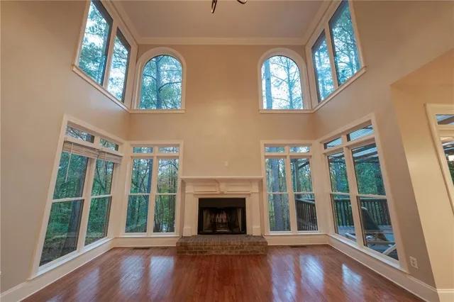 a view of an empty room with wooden floor fireplace and a window