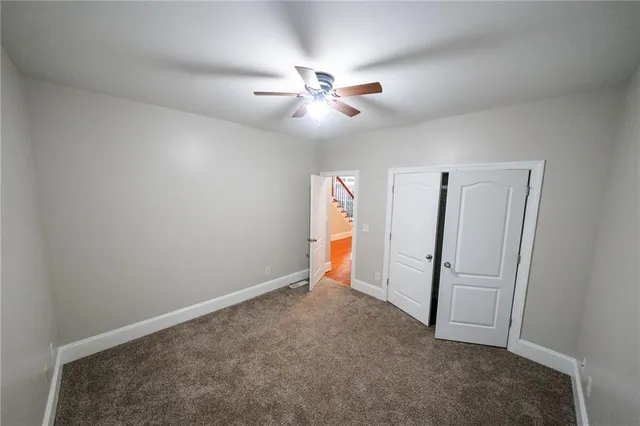 an empty room with closet and a ceiling fan