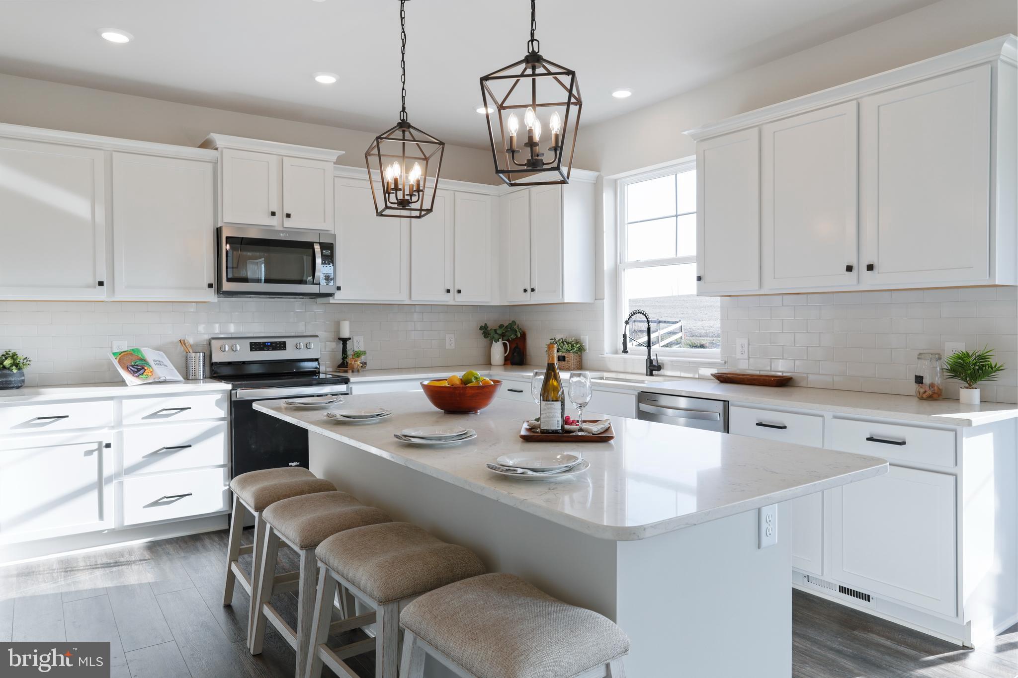 a kitchen with stainless steel appliances granite countertop a sink a stove a microwave a refrigerator a white table and cabinets