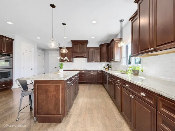 a large kitchen with stainless steel appliances kitchen island granite countertop a sink a stove and a refrigerator