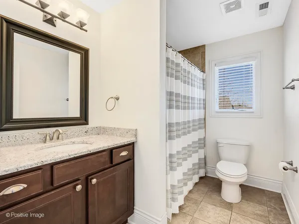 a bathroom with a granite countertop toilet a sink a mirror a lamp and a window