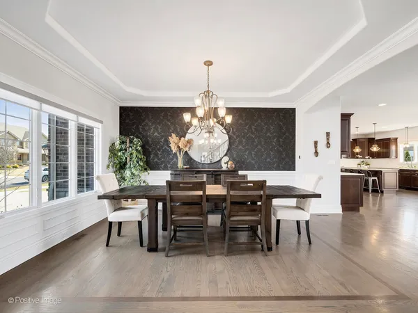 a dining room with wooden floor a chandelier a wooden table and chairs