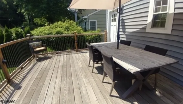 a view of deck with table and chairs a barbeque with wooden floor and fence