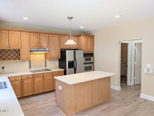 a large kitchen with stainless steel appliances a large counter top a sink a refrigerator and a window