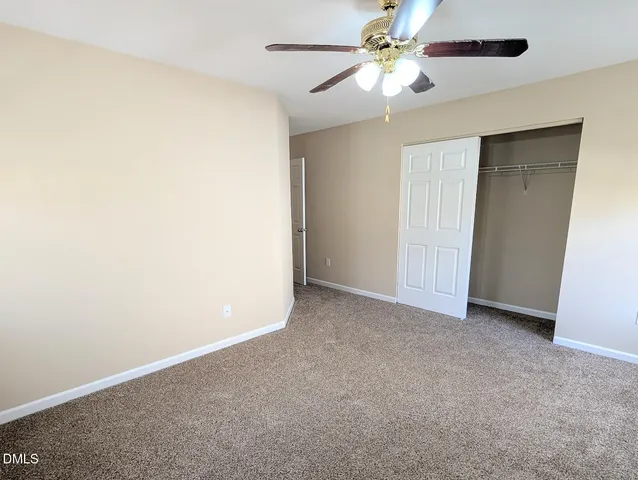 an empty room with closet and a ceiling fan