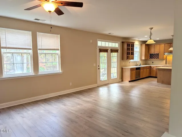 a large kitchen with stainless steel appliances wooden floor and large window
