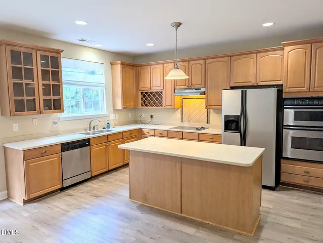 a large kitchen with stainless steel appliances a large window and a refrigerator