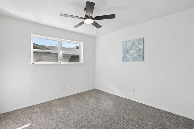 an empty room with a window and a ceiling fan