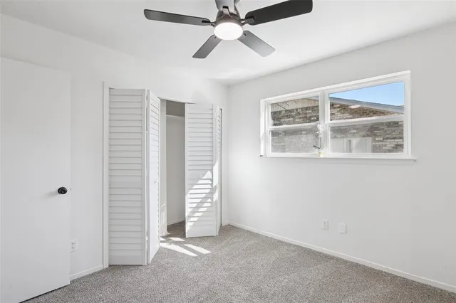 an empty room with windows and ceiling fan