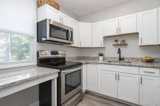 a kitchen with granite countertop white cabinets and appliances