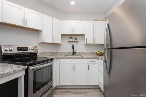 a kitchen with stainless steel appliances granite countertop a refrigerator stove and white cabinets