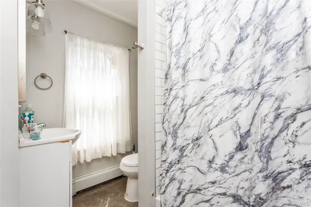 a bathroom with a granite countertop sink a toilet and shower curtain