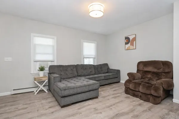 a living room with couches and a potted plant next to a window