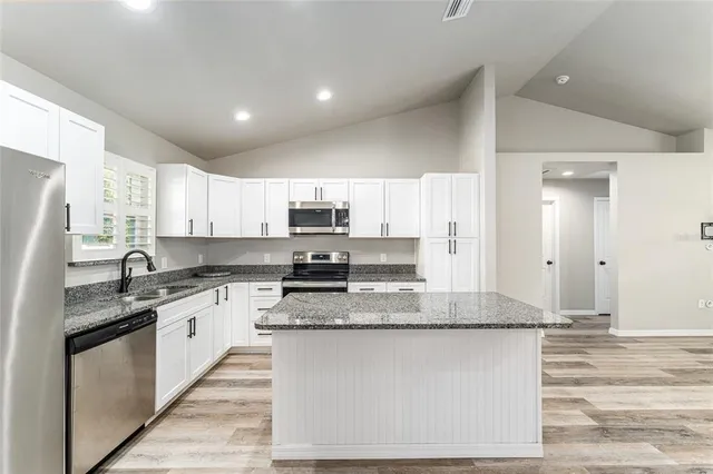 a large kitchen with stainless steel appliances granite countertop a sink stove and refrigerator