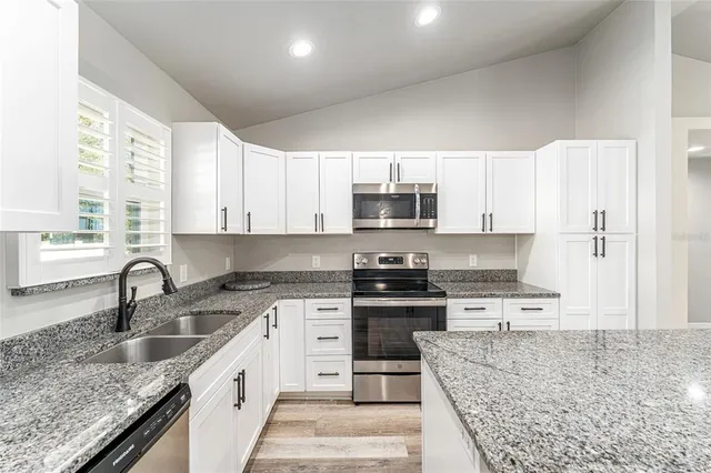 a kitchen with stainless steel appliances granite countertop white cabinets granite counter tops and a window