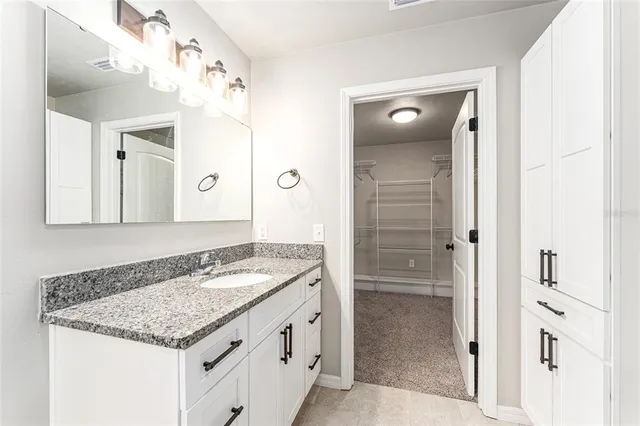 a bathroom with a granite countertop sink a mirror and shower