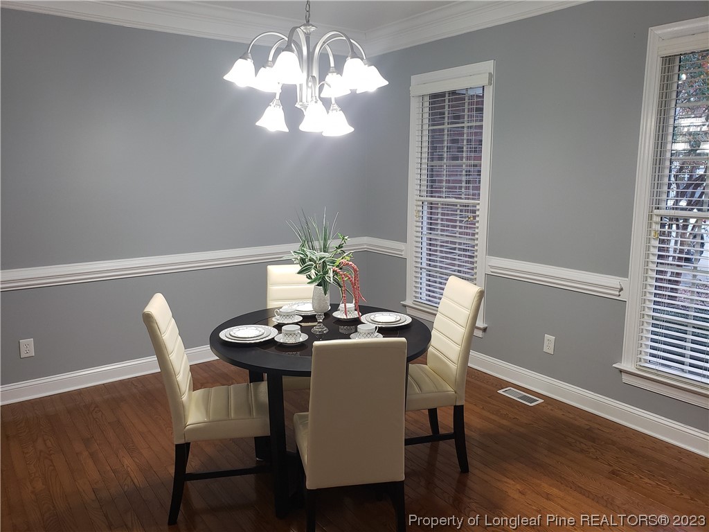 115 Blue Pine Drive Spring Lake, NC 28390 - Photo 7 of 48 a dining room with wooden floor a chandelier a wooden table and chairs